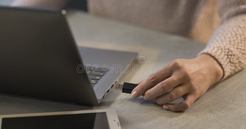 Woman plugging a USB flash drive into her laptop stock photo