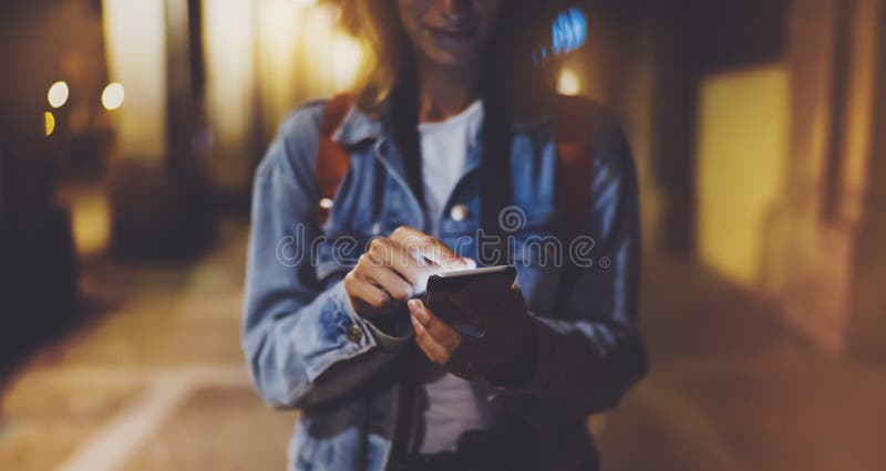 Woman pointing finger on blank screen smartphone on background bokeh light in night atmospheric city, blogger hipster using in han
