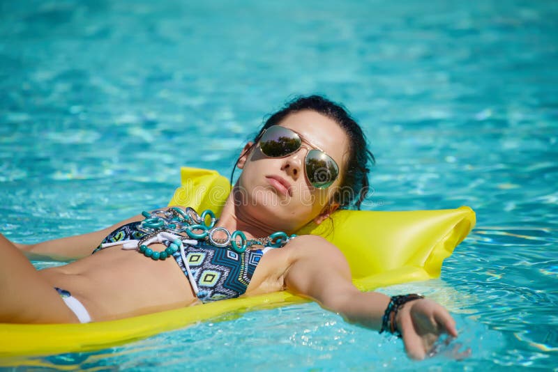 A woman in the pool floats on a blown mattress