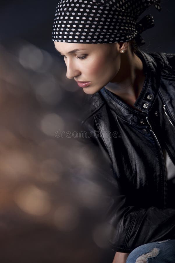 Portrét mladej žene v šatkou a koženú bundu cez tmavé pozadie.
