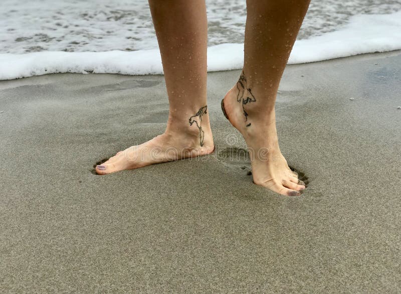 WOMAN POSES in the SAND with ANKLE TATTOOS of a MAP of the 7 CONTINENTS  Stock Photo - Image of shot, beach: 107429756