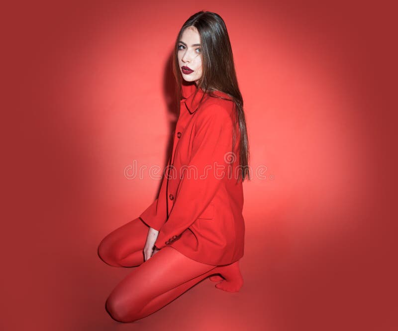 Woman with posing in total red outfit. Fashion concept. Girl on calm face in red formal jacket and tights, red