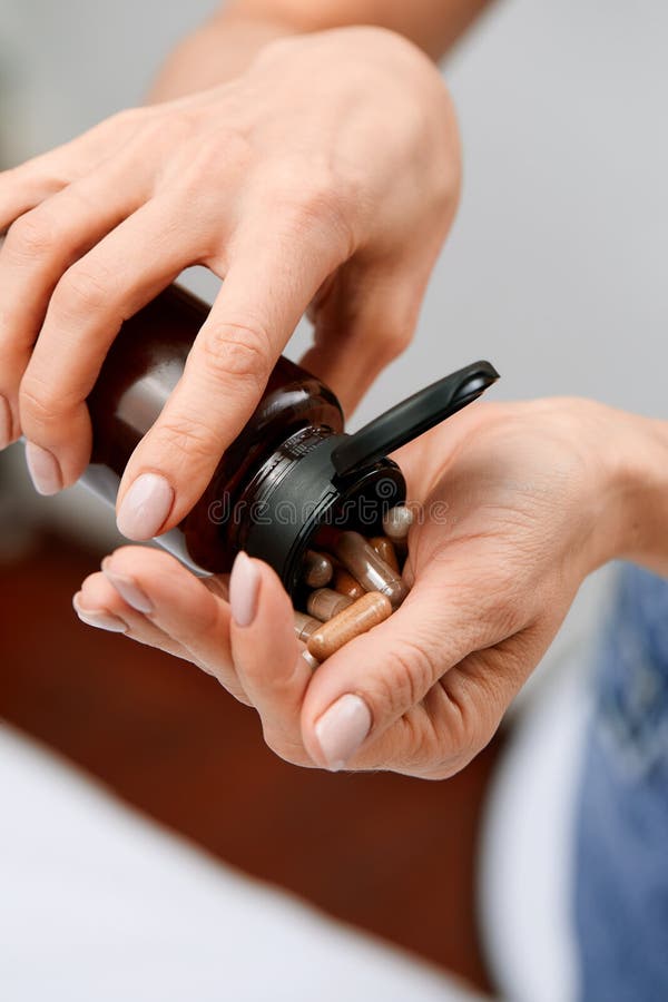 Woman pours pills or vitamins from a jar onto her hand. Taking vitamins or medications. The concept of health care, medicine, pharmacies, disease prevention. A jar with pills or vitamins in the hands