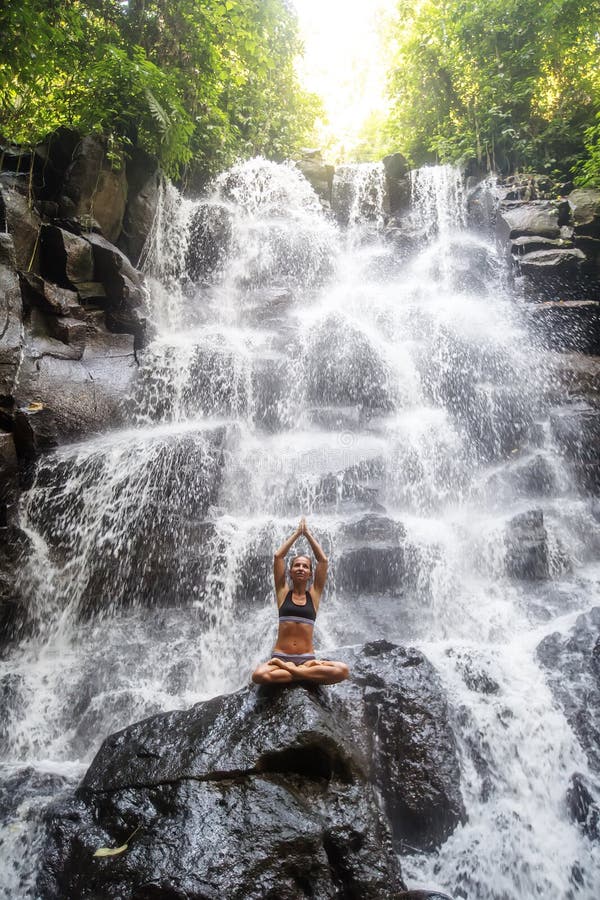 Woman practices yoga near waterfall in Bali, Indonesia stock image Woman practices yoga near waterfall in Bali, Indonesia stock image