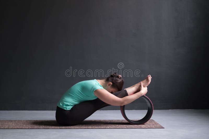 Woman Practicing Yoga, Seated Forward Bend Pose, Working Out, Using Wheel  Stock Photo - Image of head, pose: 138148506