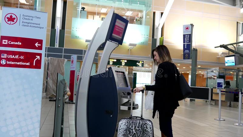 Woman printing out luggage tag at Air Canada machine