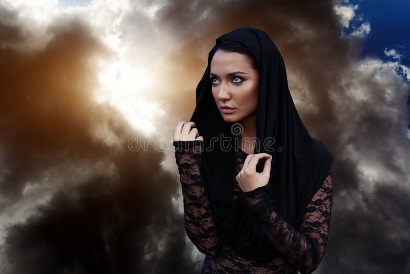 A woman is a prophet sorcerer and a preacher in a black mystical cloak with a hood against a dramatic background... royalty free stock photo A woman is a prophet sorcerer and a preacher in a black mystical cloak with a hood against a dramatic background... royalty free stock photo