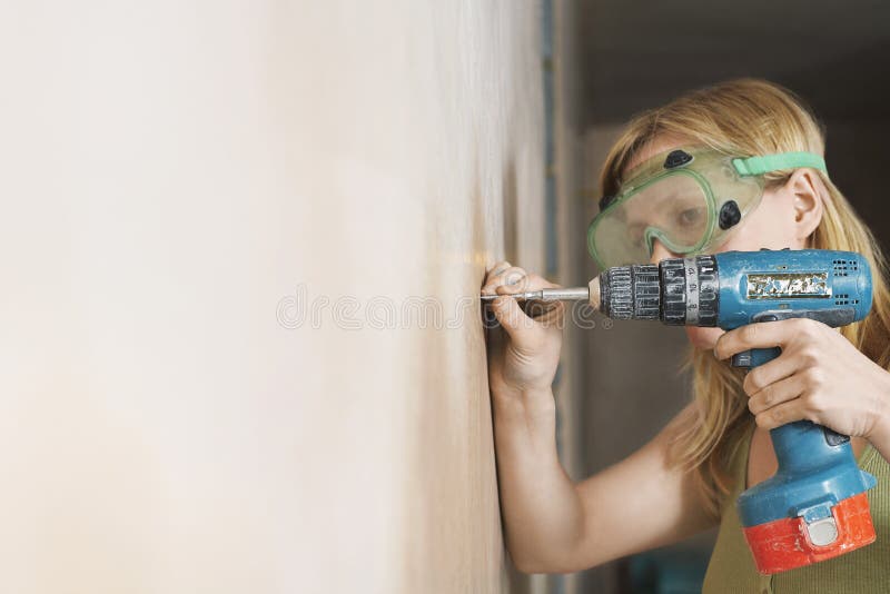 Woman In Protective Goggles Drilling Wall