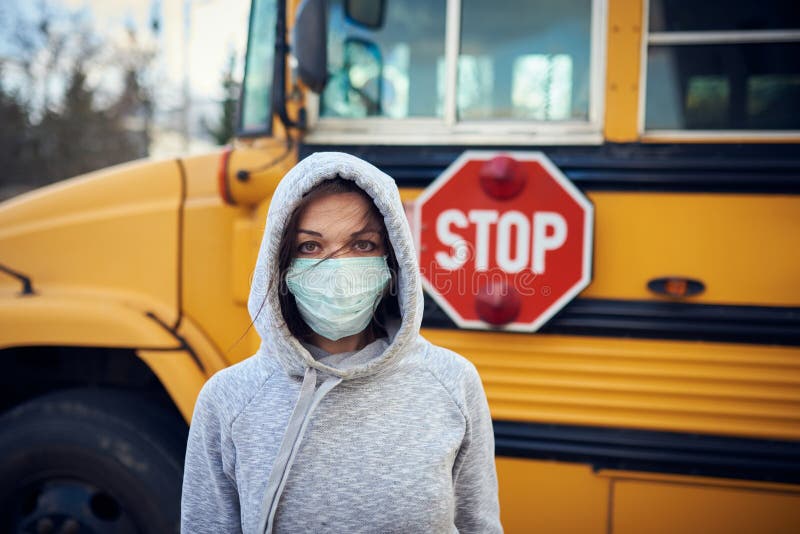 A woman in a protective mask stands on the background of a school bus. A large stop sign is visible on the background royalty free stock photography A woman in a protective mask stands on the background of a school bus. A large stop sign is visible on the background royalty free stock photography