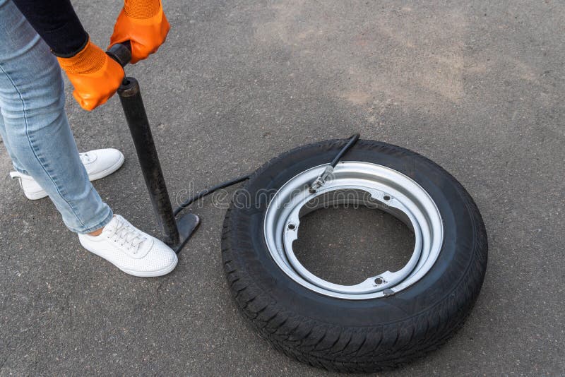 A Man Pumps Air into the Wheel of an Electric Scooter Using a Special