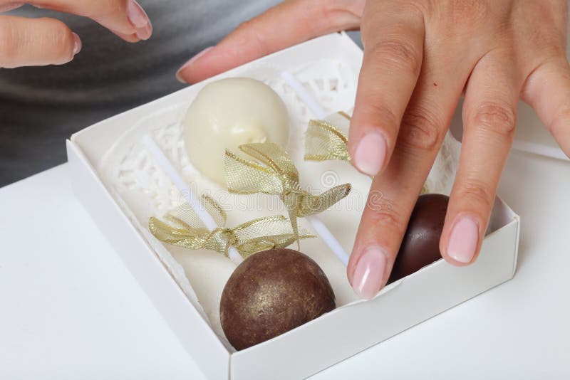 Woman puts cake pops in a gift box. Scissor wand candy. Candies are decorated with ribbons stock image Woman puts cake pops in a gift box. Scissor wand candy. Candies are decorated with ribbons stock image