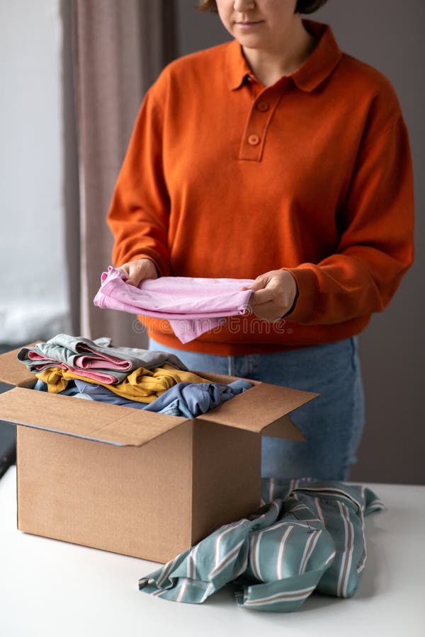 Woman puts clothes in cardboard box for donation royalty free stock images