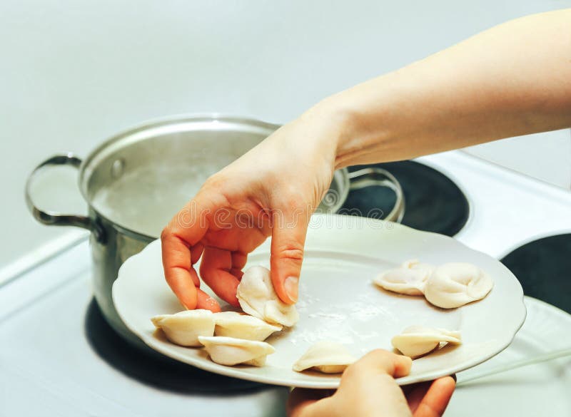 A woman puts dumplings in boiling water stock photos A woman puts dumplings in boiling water stock photos