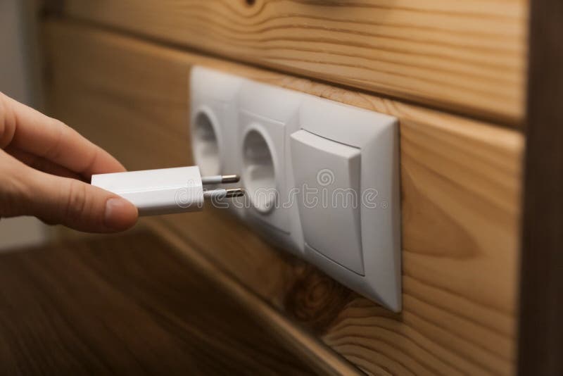 Woman Putting Charging Plug with USB Cable into Socket on Wall Stock