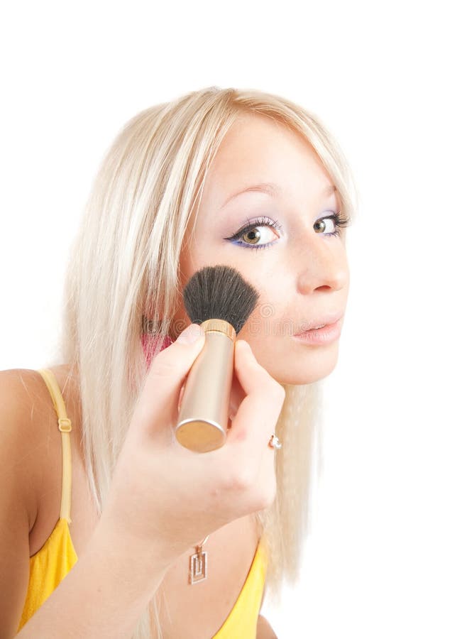 Woman putting make up on her face with a brush