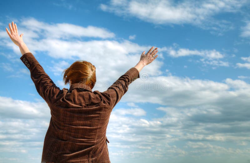 Woman with raised hands against blue sky