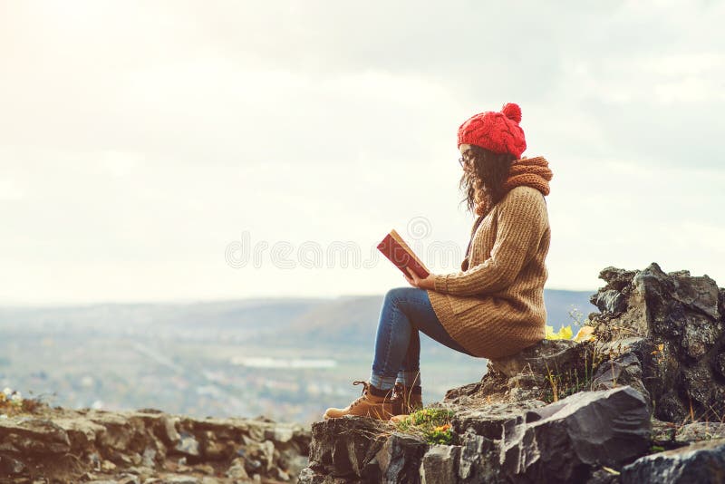 Woman reading book on the top of rock in autumn day. royalty free stock photo Woman reading book on the top of rock in autumn day. royalty free stock photo