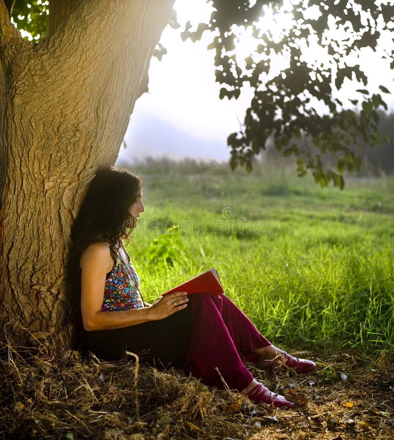 Woman sitting under tree reading a book. Woman sitting under tree reading a book