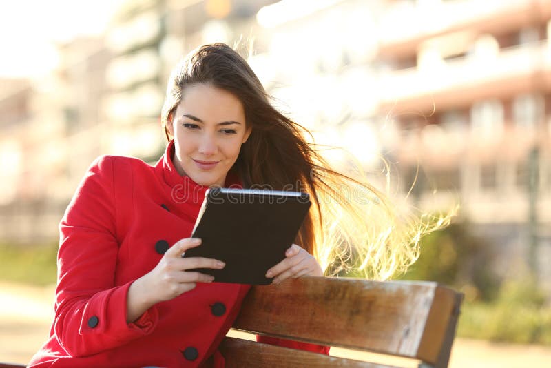 Woman reading an ebook or tablet in an urban park stock photos