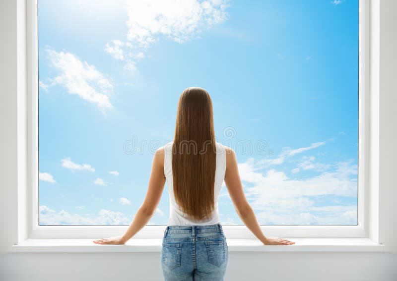 Woman Rear View looking at Window. Young Girl Back Side Silhouette look forward and thinking. Morning wake up Woman. Sky. Woman Rear View looking forward trough