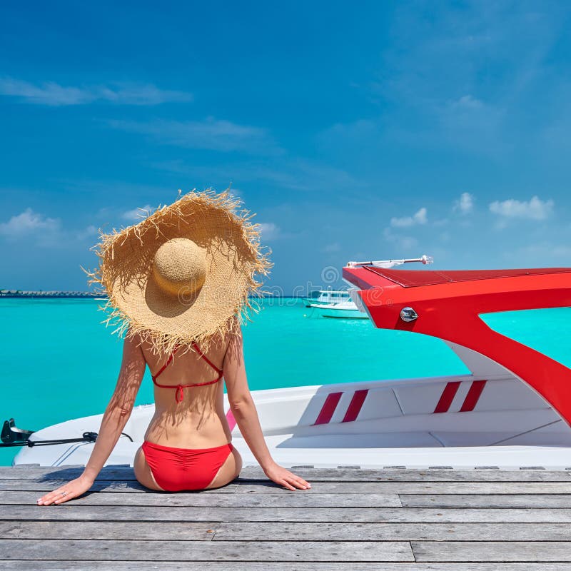 Woman in bikini sitting on jetty with boat stock image Woman in bikini sitting on jetty with boat stock image