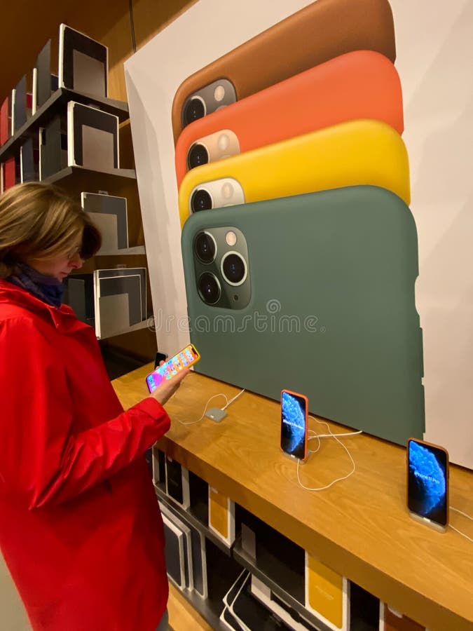 Woman in red coat inside Apple Computers Store testing the new latest iPhone 11 Pro smartphone stock photos Woman in red coat inside Apple Computers Store testing the new latest iPhone 11 Pro smartphone stock photos