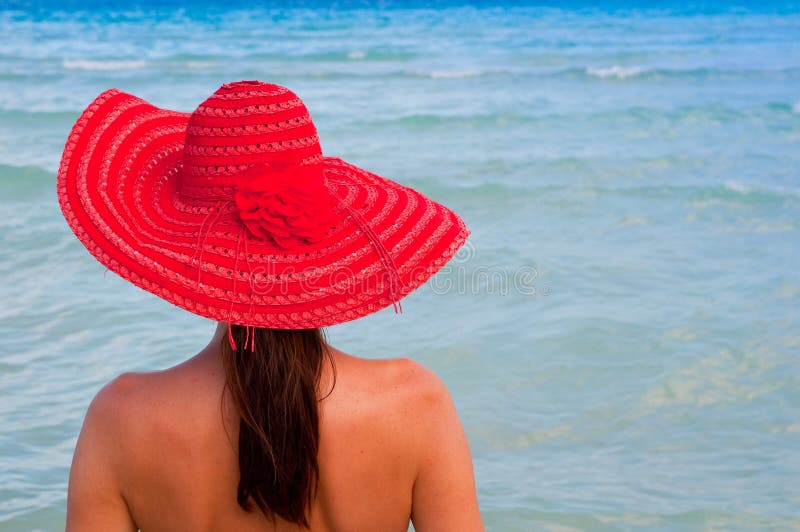 Woman with red hat looking at the sea