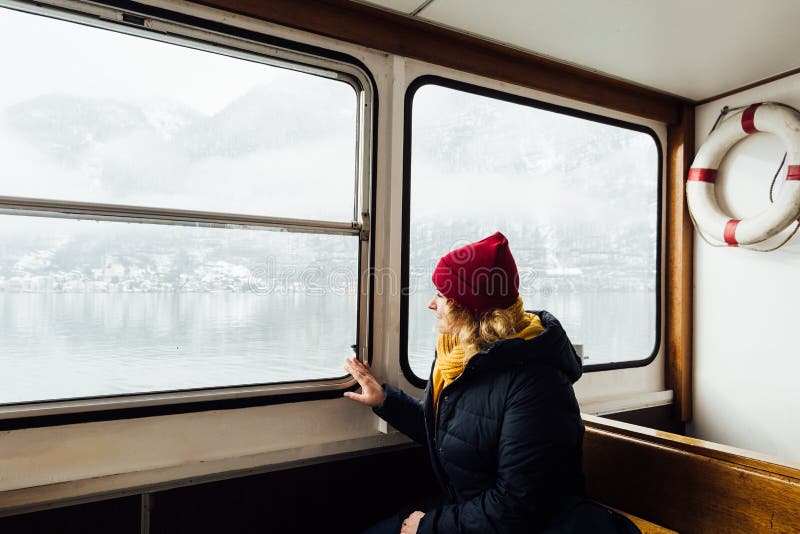 Woman in red hat sitting inside the ferry on the way to Hallstatt, Austria