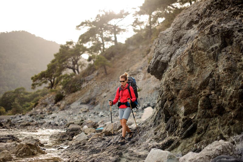 Woman with hiking equipment trekking through stoney coast royalty free stock photo Woman with hiking equipment trekking through stoney coast royalty free stock photo