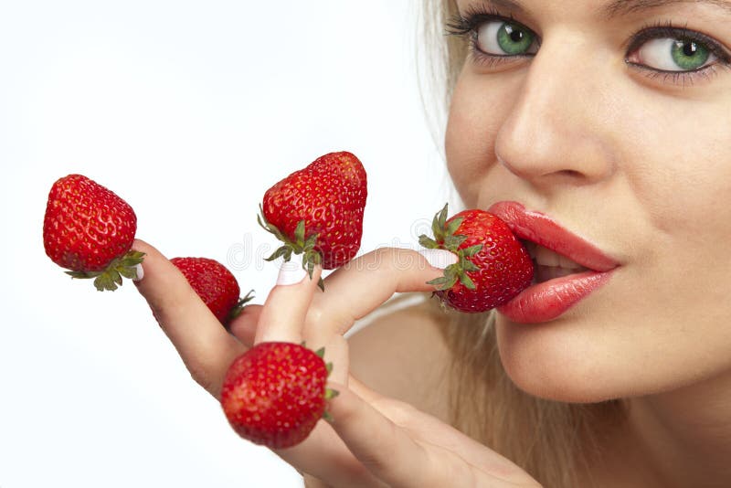 Woman with red strawberries picked on fingertips