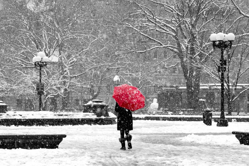 Woman with red umbrella walking through black and white landscape during norâ€™easter snow storm in Washington Square Park, New York City. Woman with red umbrella walking through black and white landscape during norâ€™easter snow storm in Washington Square Park, New York City