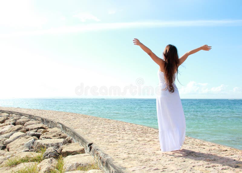Woman relaxing at the beach with arms open enjoying her freedom