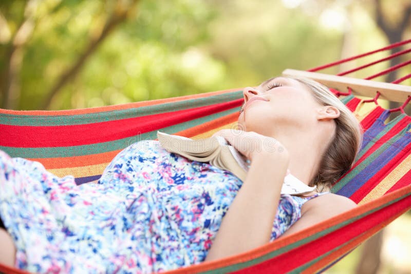 Woman Relaxing In Hammock With Book During Summer