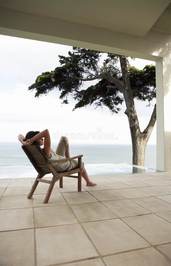 Woman Relaxing On Lounge Chair By Infinity Pool