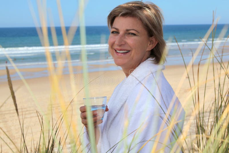 Woman relaxing by the sea with a glass of water