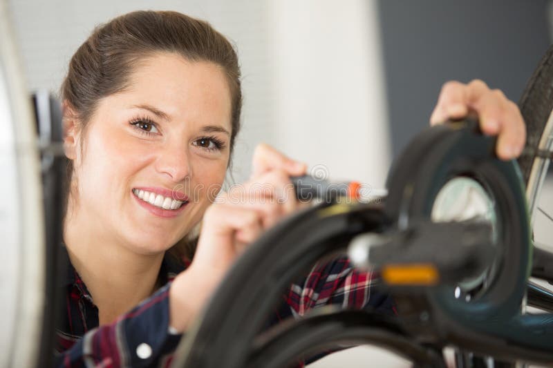 Woman repairs bicycle whee screw key stock photos