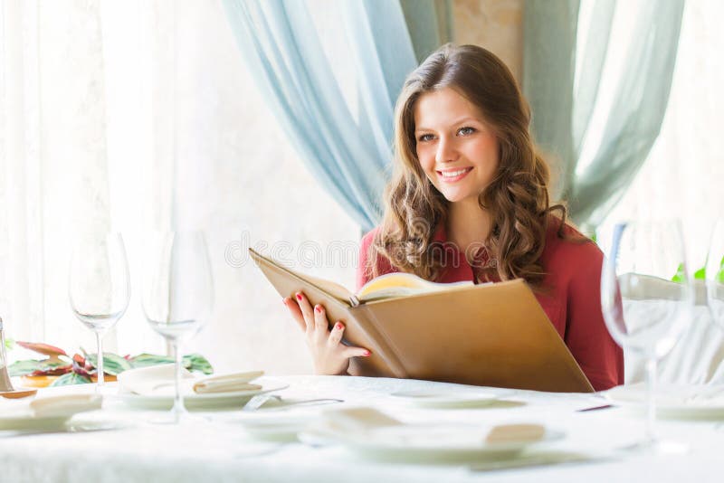 A woman in a restaurant with the menu in hands stock images