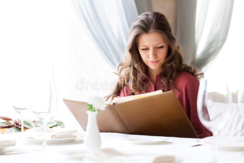 A woman in a restaurant with the menu in hands royalty free stock photography