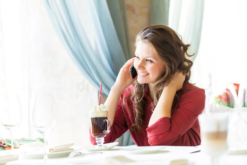 A woman in restaurant is talking to mobile phone royalty free stock image