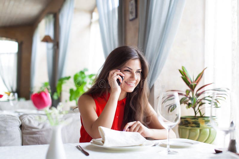 Woman in restaurant is talking to mobile phone stock photography