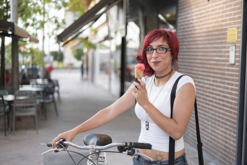 Woman with ride bike in the city and eats ice cream in sum stock photo Woman with ride bike in the city and eats ice cream in sum stock photo