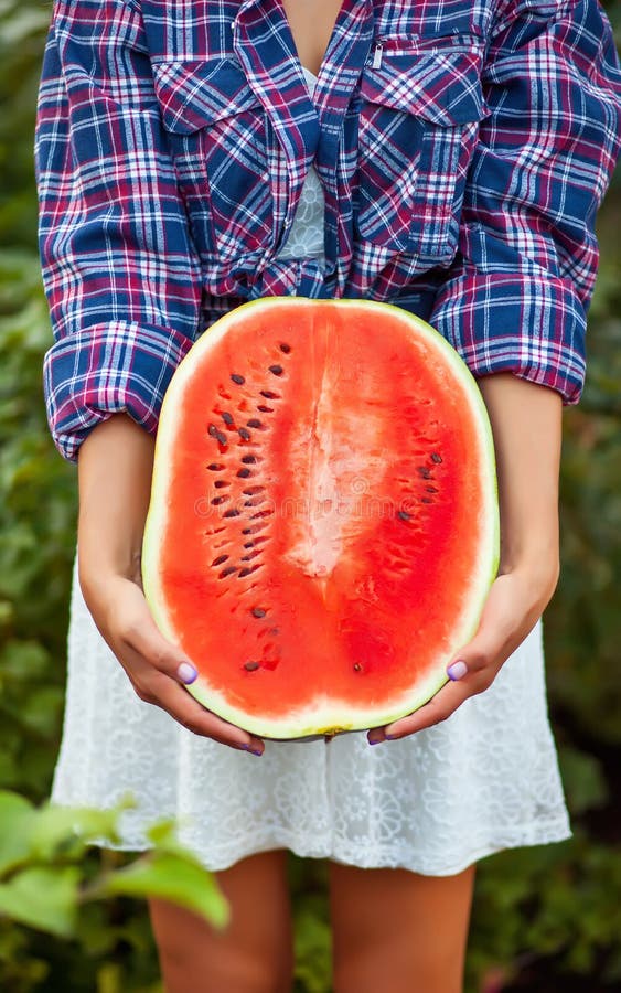 Woman with a ripe watermelon in a garden. 