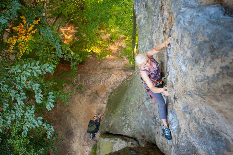 Woman rock climber is climbing on a rocky wall