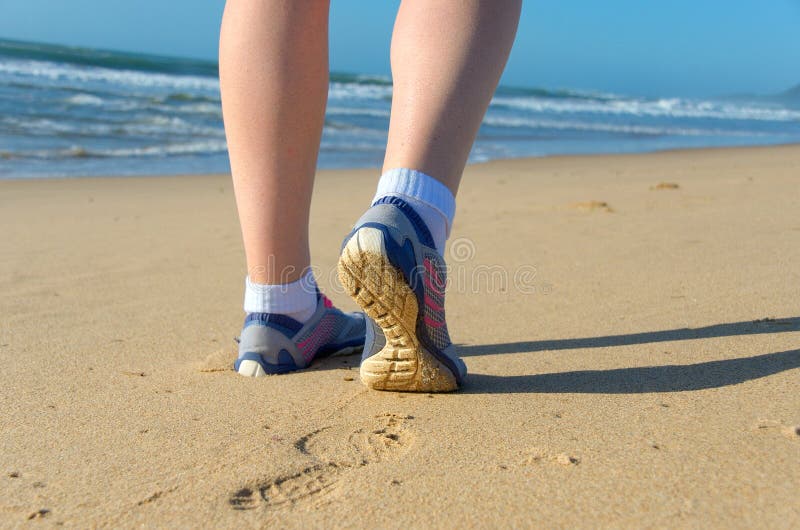 Woman runner legs in shoes on beach, running and sport concept