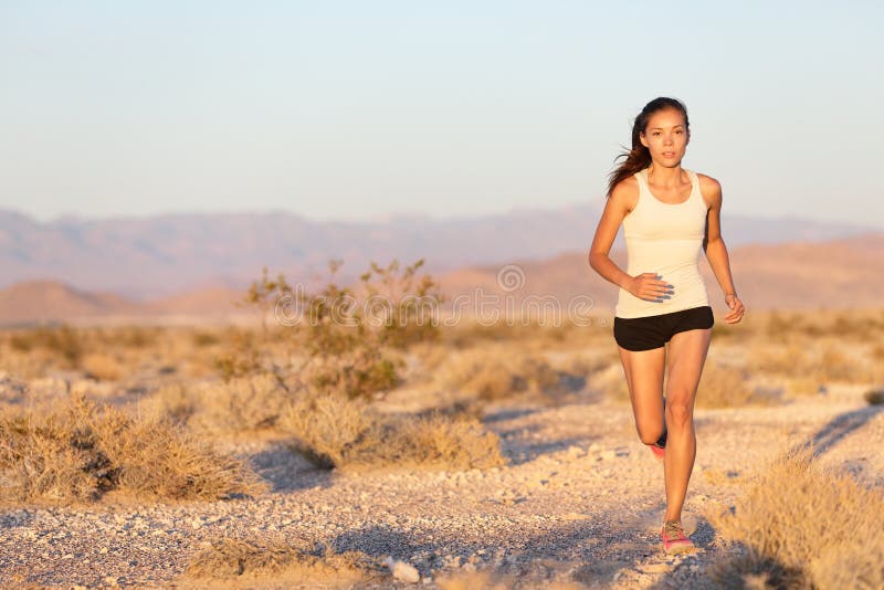 Woman runner running cross country trail run. Female jogger training outside on path outdoors at summer sunset. Beautiful young fitness model with healthy lifestyle . Mixed race Asian Caucasian girl.