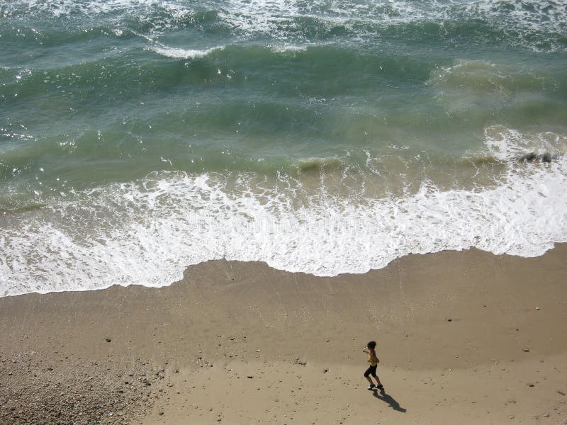 La donna in esecuzione e l'azzurro del mare, una giovane donna in esecuzione in una bellissima spiaggia, il mare blu e la spiaggia e la donna, la donna in esecuzione.