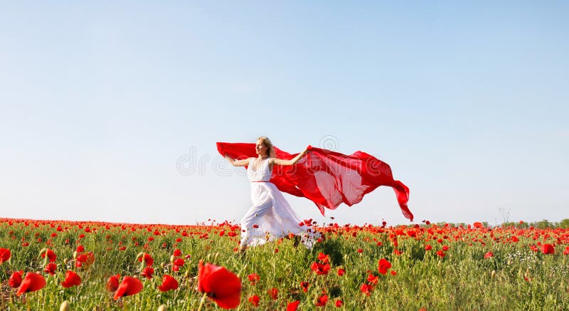 Woman running with red scarf in poppy field