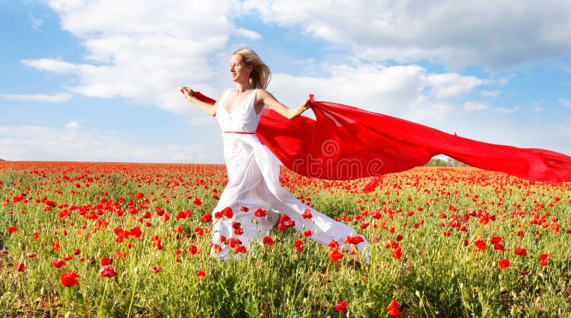 Woman running with red scarf in poppy field