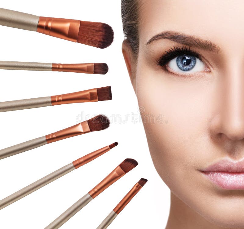 Woman`s face surrounded by makeup brushes.