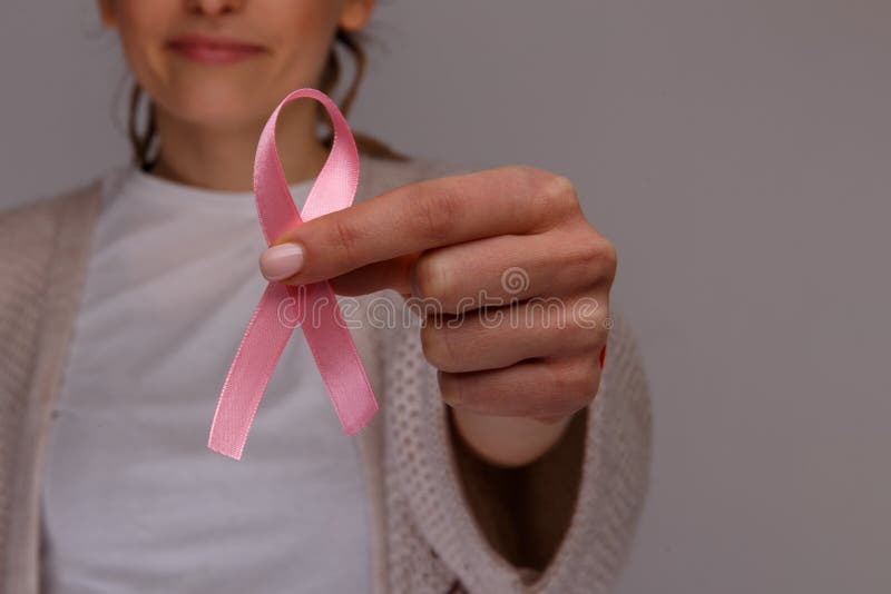 Woman`s hand holding pink ribbon .